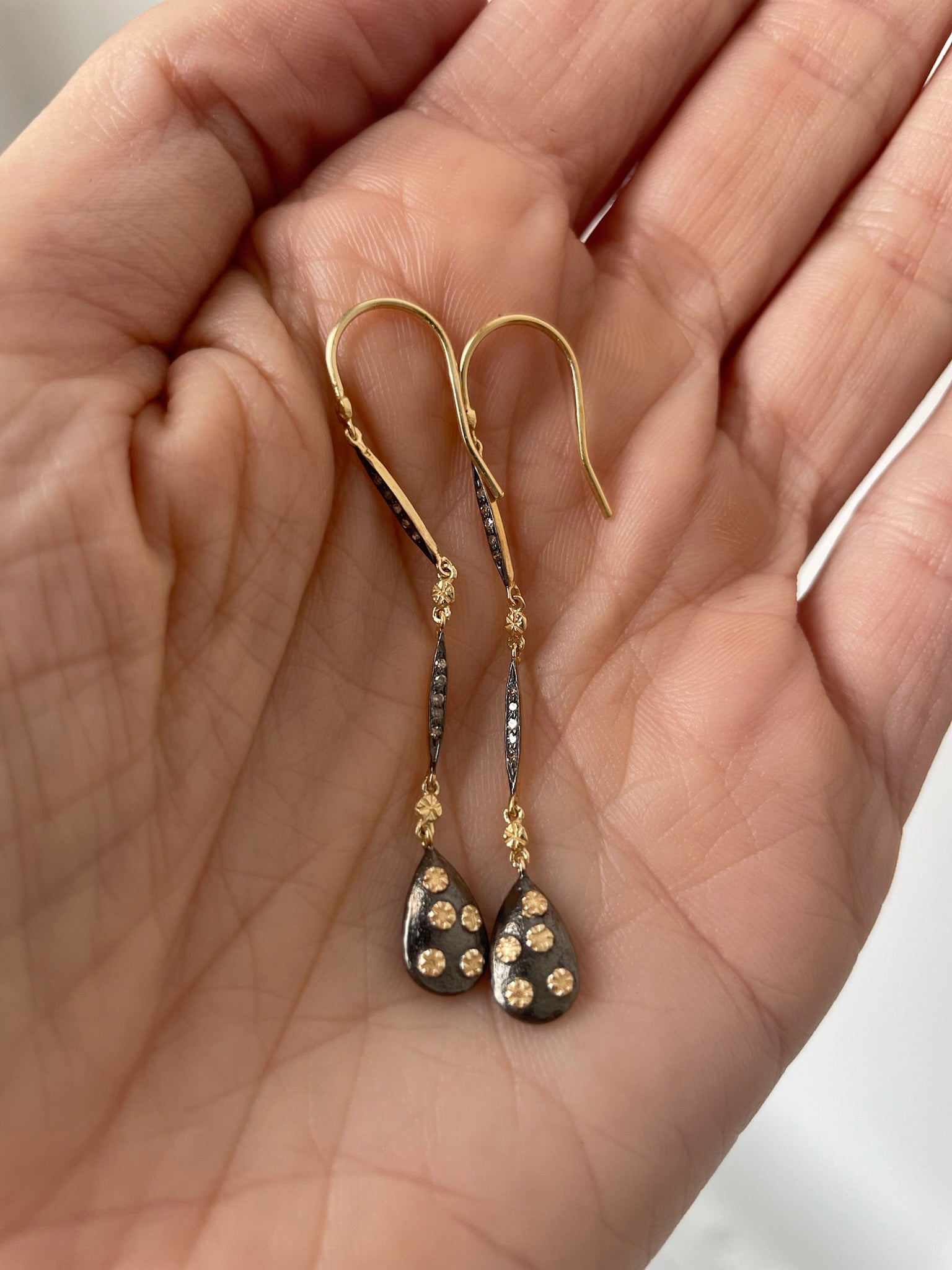 teardrop shaped dangly earrings made of gold and oxidized silver 