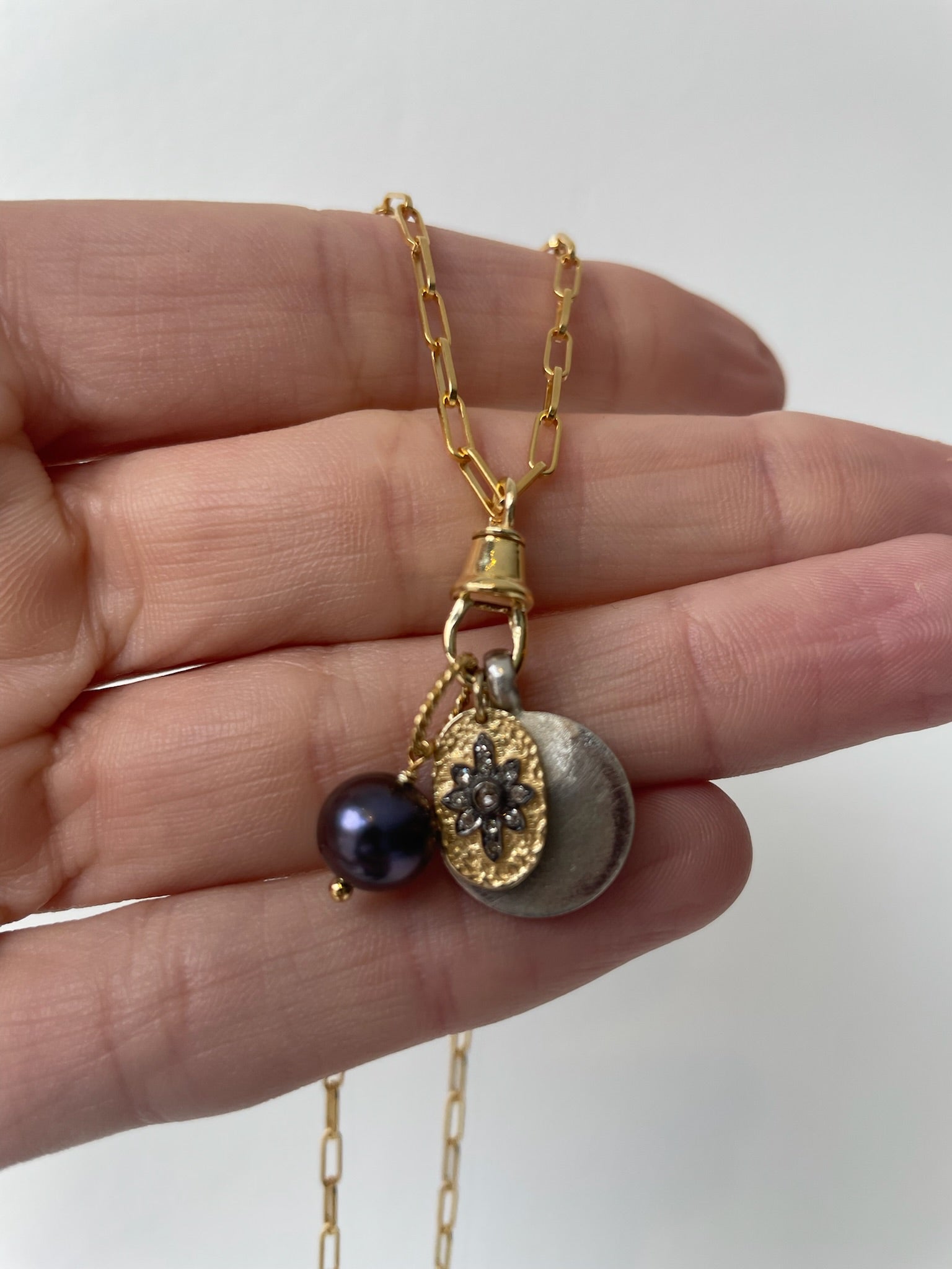 Gold charm necklace with small locket, freshwater pearl, oxidized silver pendant