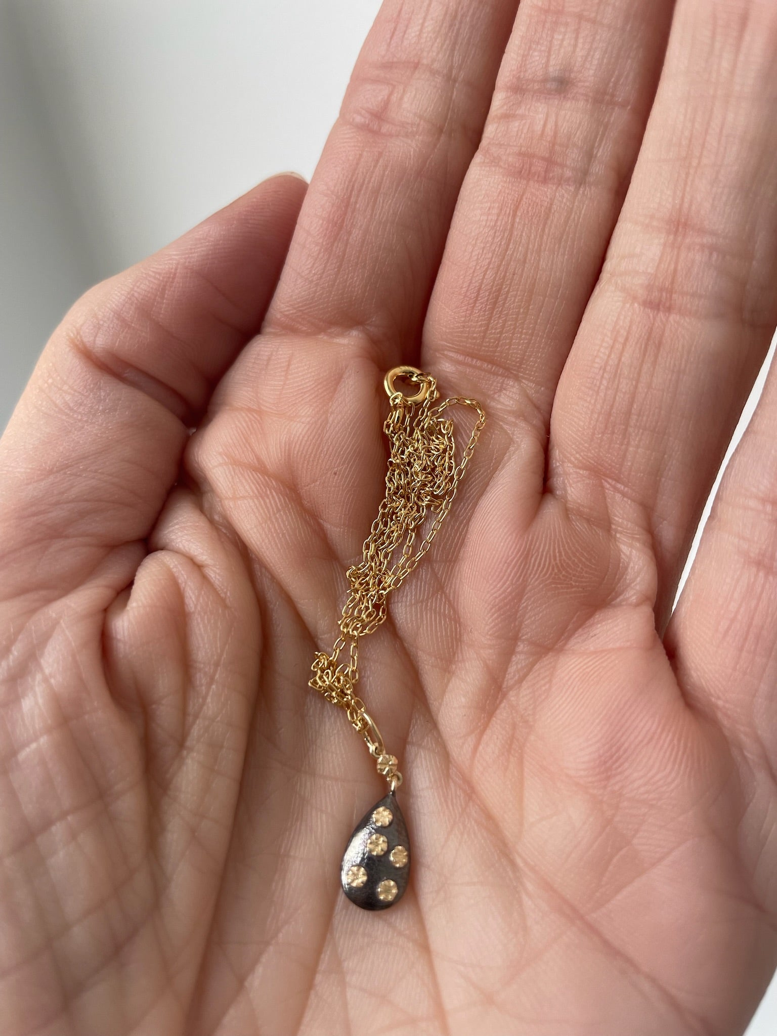 Dainty gold necklace with small oxidized silver pendant