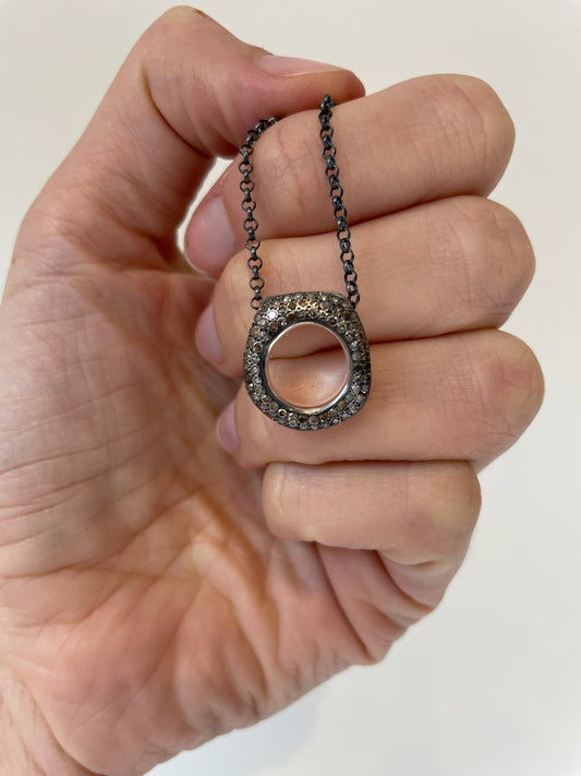 Long sterling silver necklace with circular pendant encrusted in diamonds 