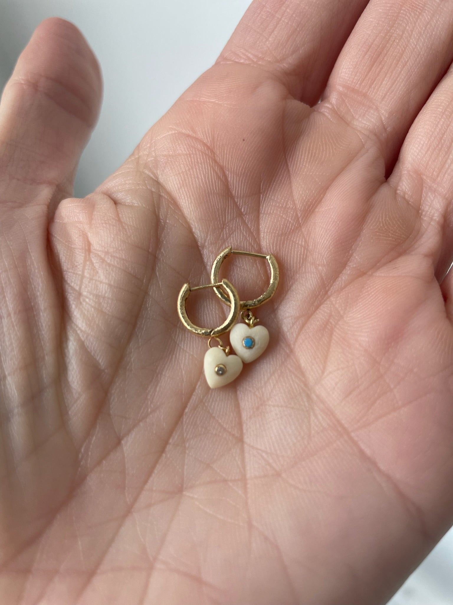 small heart earrings made of vegetal ivory and a small turquoise stone in one and a small diamond in the other 