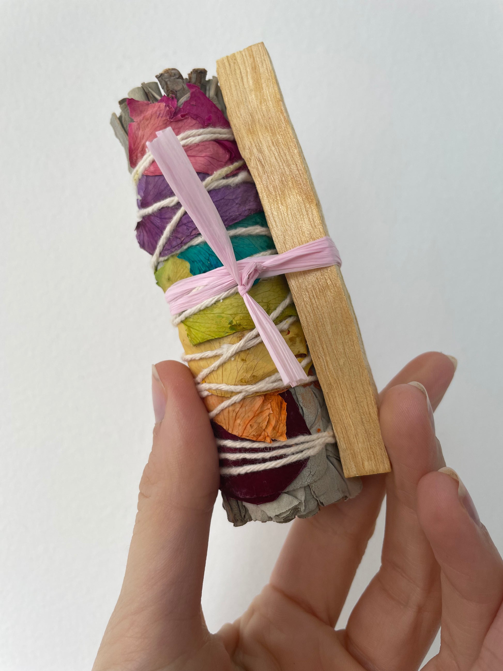 a 7 chakra smudge duo with rainbow sage wand + palo santo stick