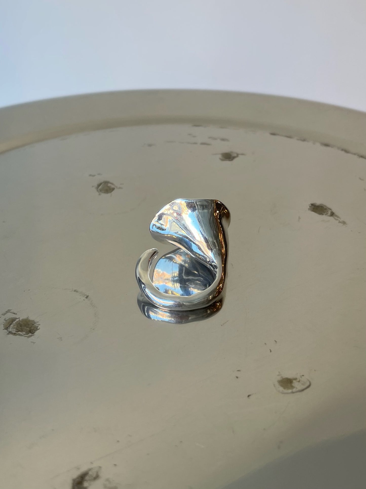 Silver ring on a white surface with visible scratches