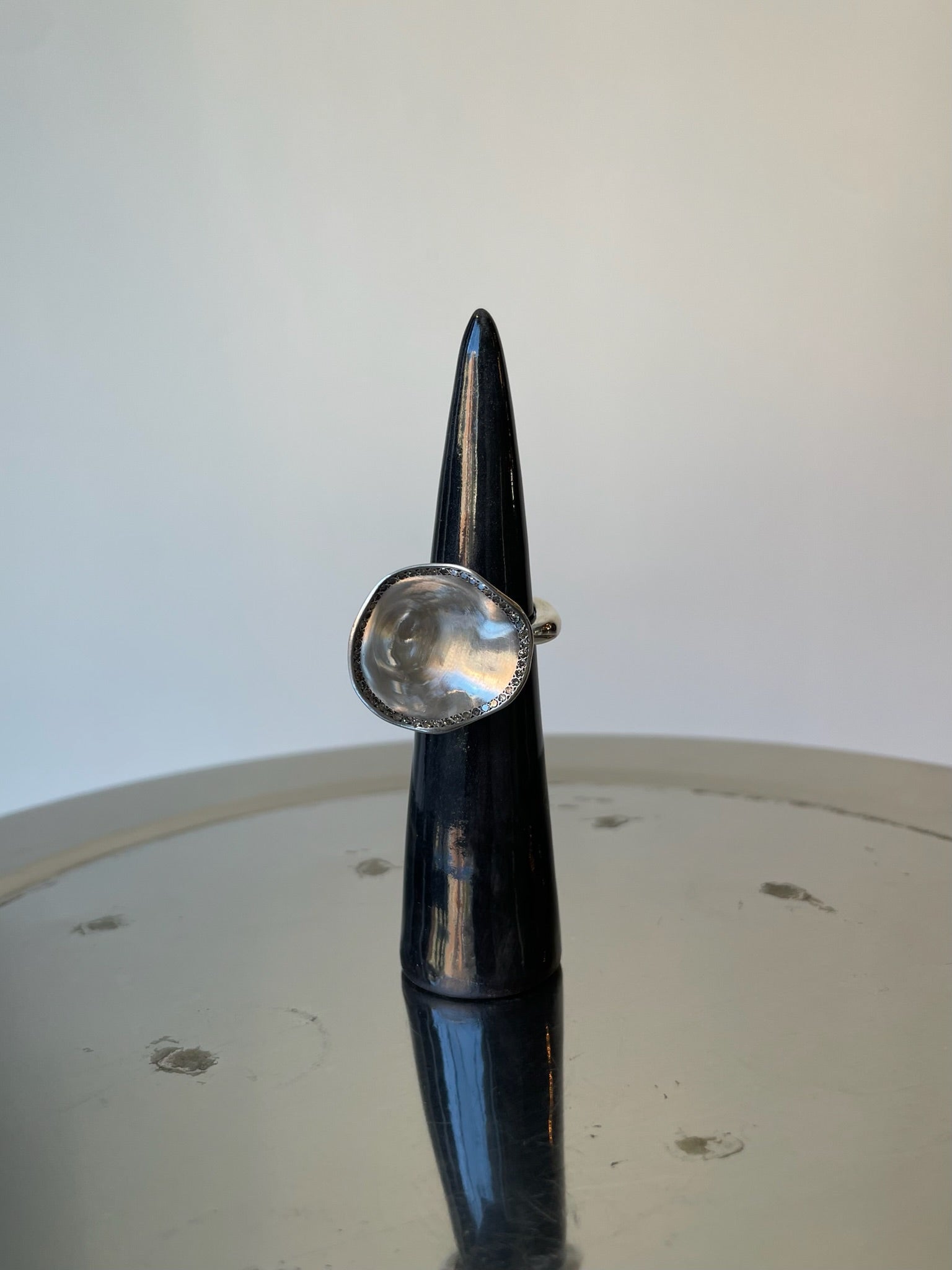 Silver ring on a black cylindrical object with a white background