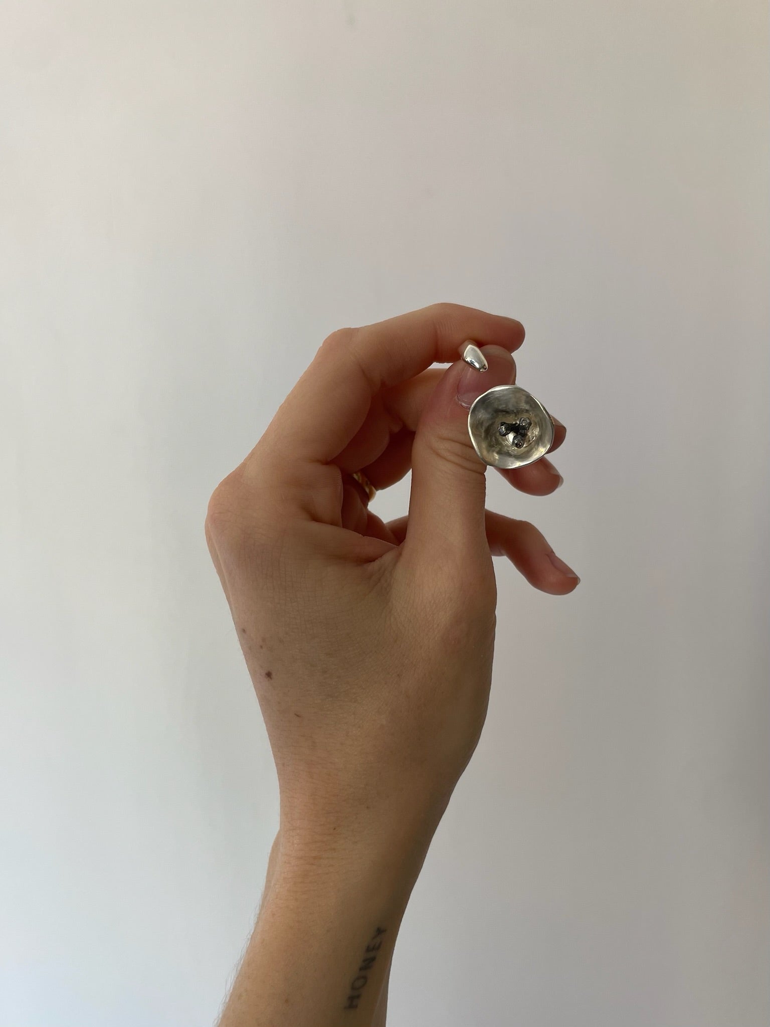Hand holding a small metallic object against a plain background